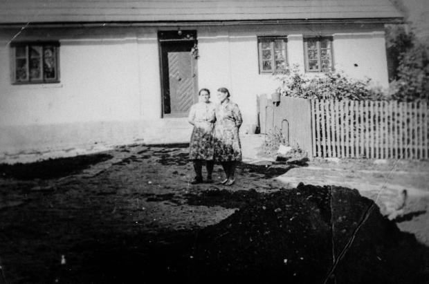 Матір Івана біля їхньої хати після переселення до України
